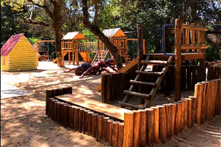 Espaço do Bosque do Saber em Indaiatuba com parquinho infantil de madeira rodeado por árvores e sombra natural.